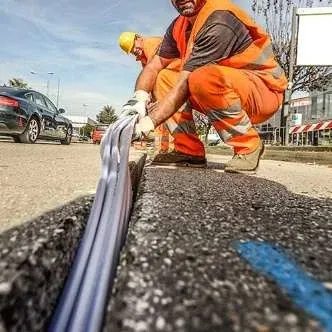 Tecnico al lavoro sulla posa della fibra ottica lungo una strada